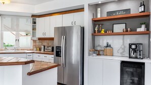 Une cuisine moderne avec des meubles blancs, un réfrigérateur en acier inoxydable, une machine à café et un lave-vaisselle encastré.