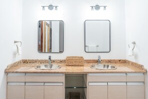 A bathroom with two sinks, a mirror, and a towel rack. - Daria Beachfront Community Steps 2 Pool- Generator (Vega Alta)