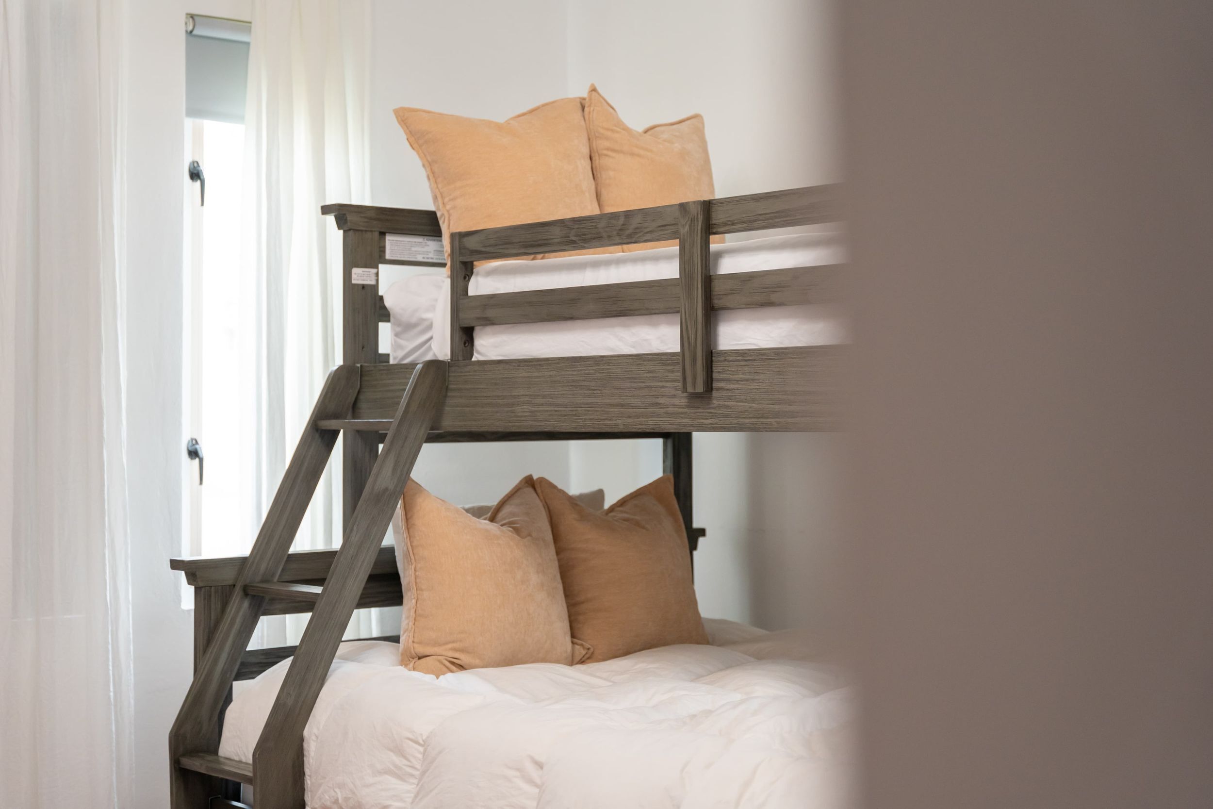 Uma beliche com grades de madeira e roupa de cama bege.