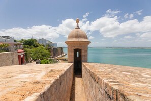 Una fortaleza de piedra con una cúpula central, un estrecho pasaje y vistas al mar.