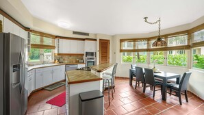 Une cuisine avec des meubles blancs, un plan de travail en bois et un coin repas comprenant une table et des chaises.