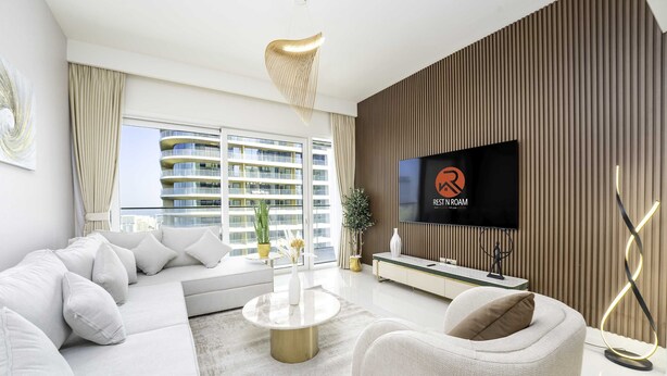 Un salon moderne avec un canapé, une table basse, un téléviseur et une vue sur un immeuble de grande hauteur.