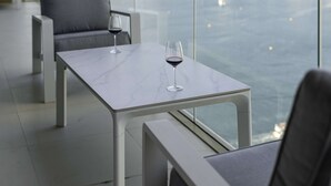 Un espace repas moderne avec une table en marbre et deux chaises, donnant sur un plan d’eau.