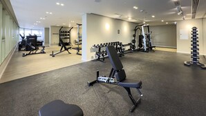 Une salle de sport moderne équipée de divers appareils d’exercice, notamment des tapis de course, des appareils de musculation et des poids libres.