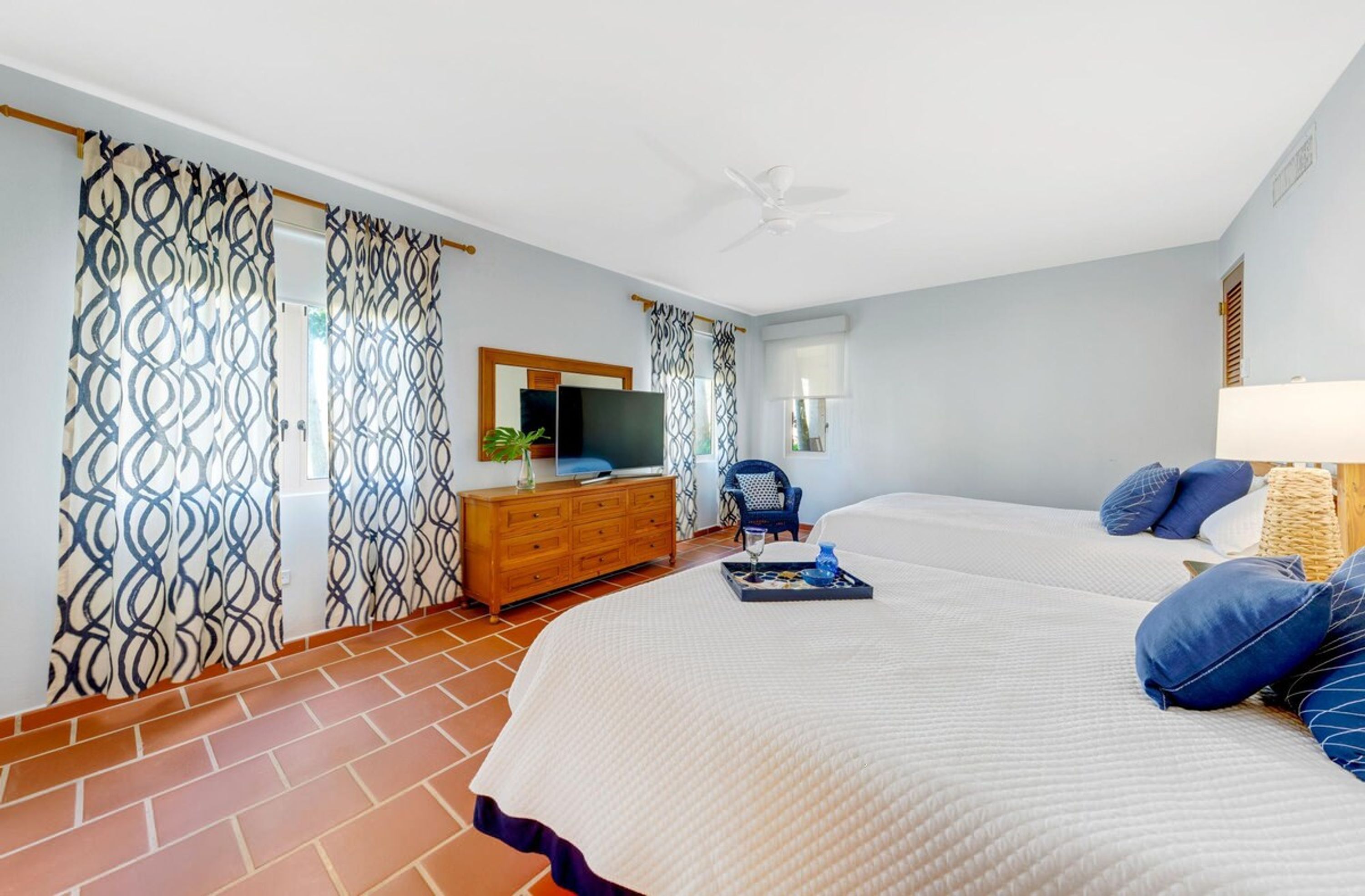 A bedroom with a bed, a dresser, a TV, and a chair.