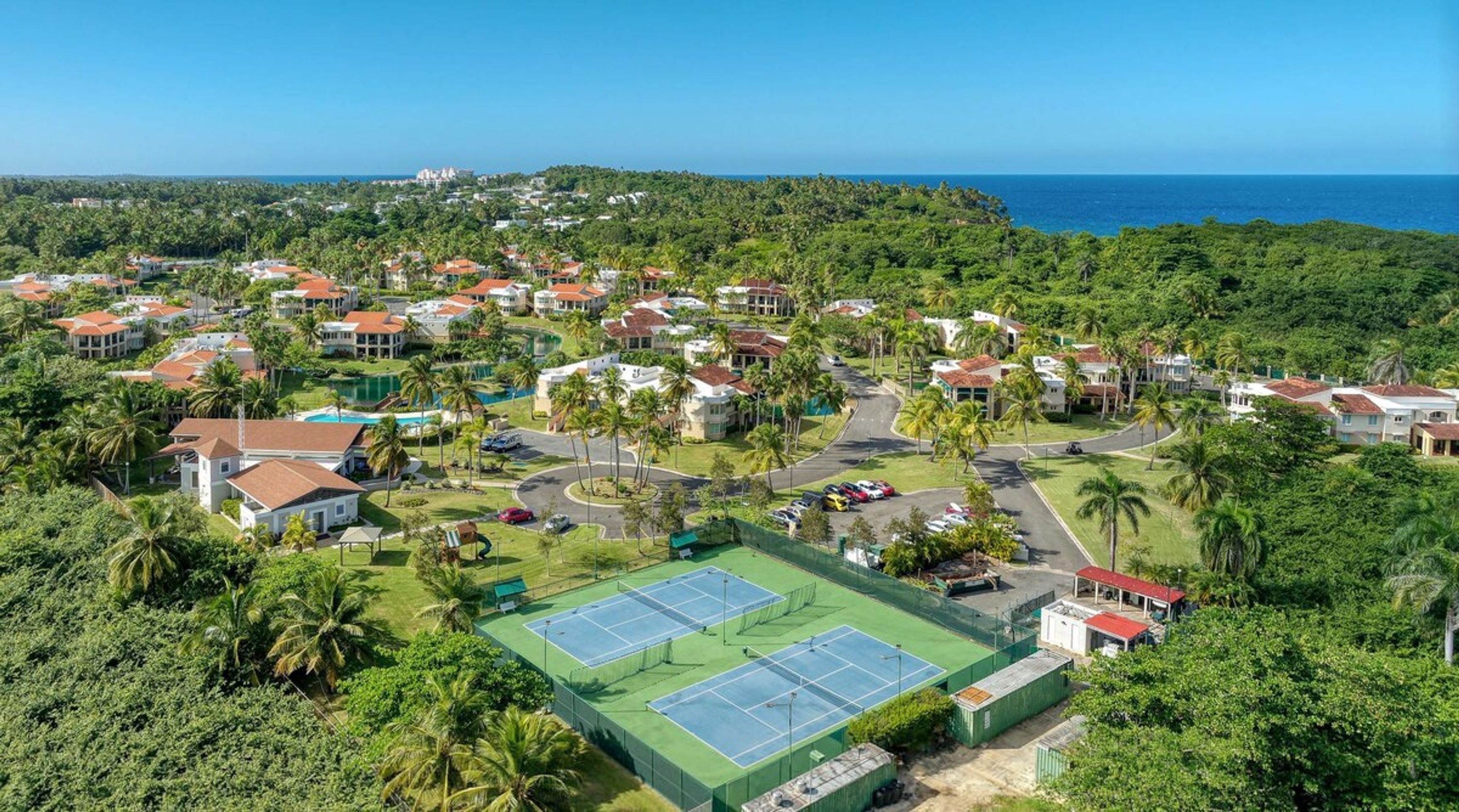 Un quartier résidentiel situé sur la côte, avec des maisons, un court de tennis et une vue sur l’océan.