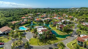 A resort with multiple buildings, a central swimming pool, and surrounding greenery. - Villa Quenepa at Lakeside Villas (Vega Alta)