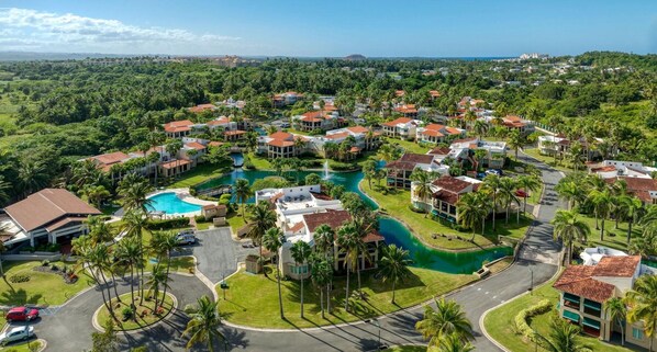 A resort with multiple buildings, a central swimming pool, and surrounding greenery. - Villa Quenepa at Lakeside Villas (Vega Alta)