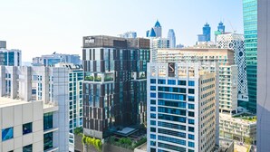 A modern cityscape with high-rise buildings, including a prominent glass building with a 'S' logo. - Luxurious Studio With Bay View in Sol Bay (Dubai)