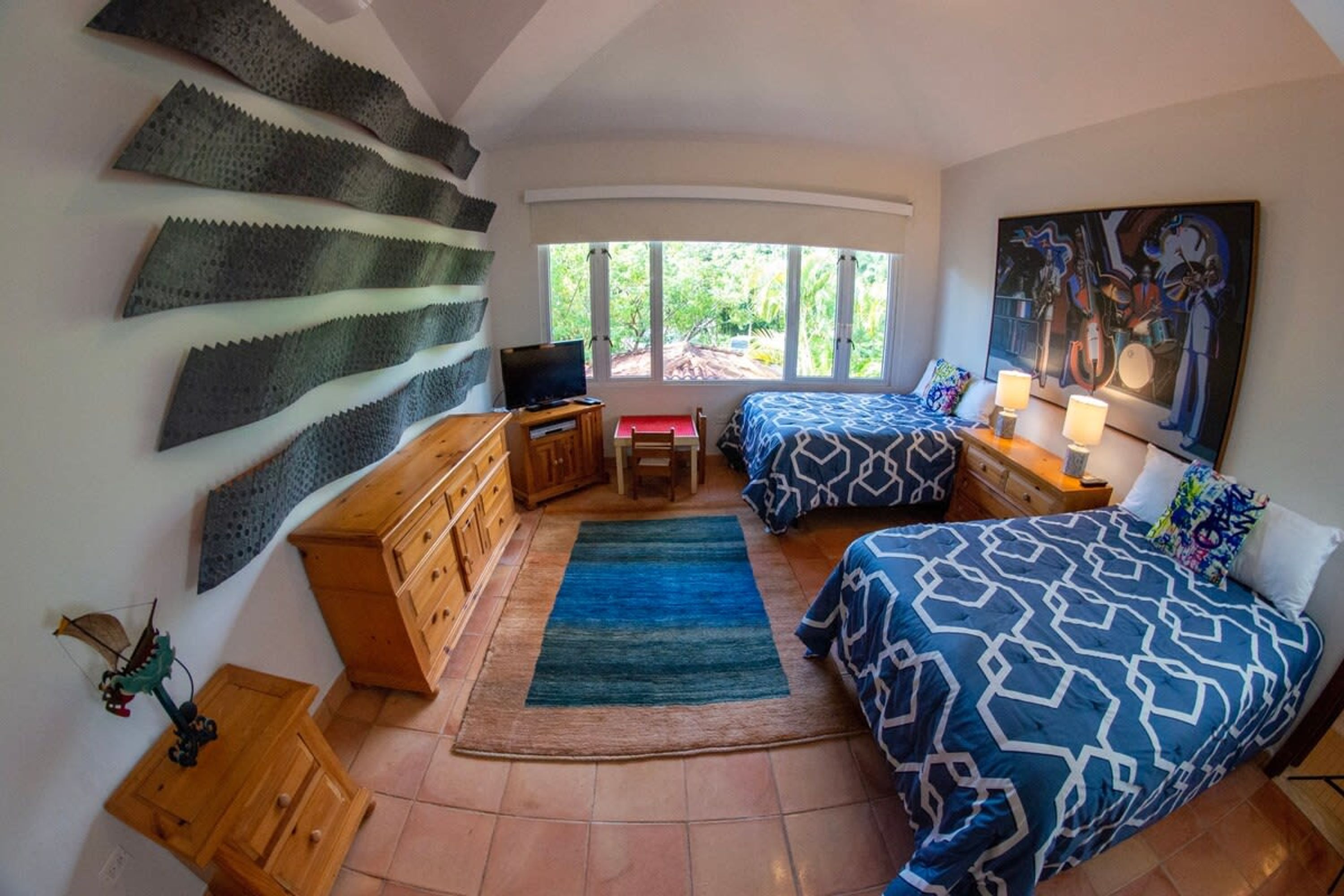 Ein Schlafzimmer mit zwei Betten, einem Fernseher, einem Schreibtisch und einem großen Fenster.