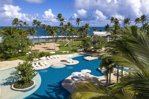 Un resort con una piscina grande, palmeras y vista al océano.