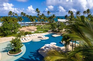 Un resort con piscina, palmeras y vista al océano.