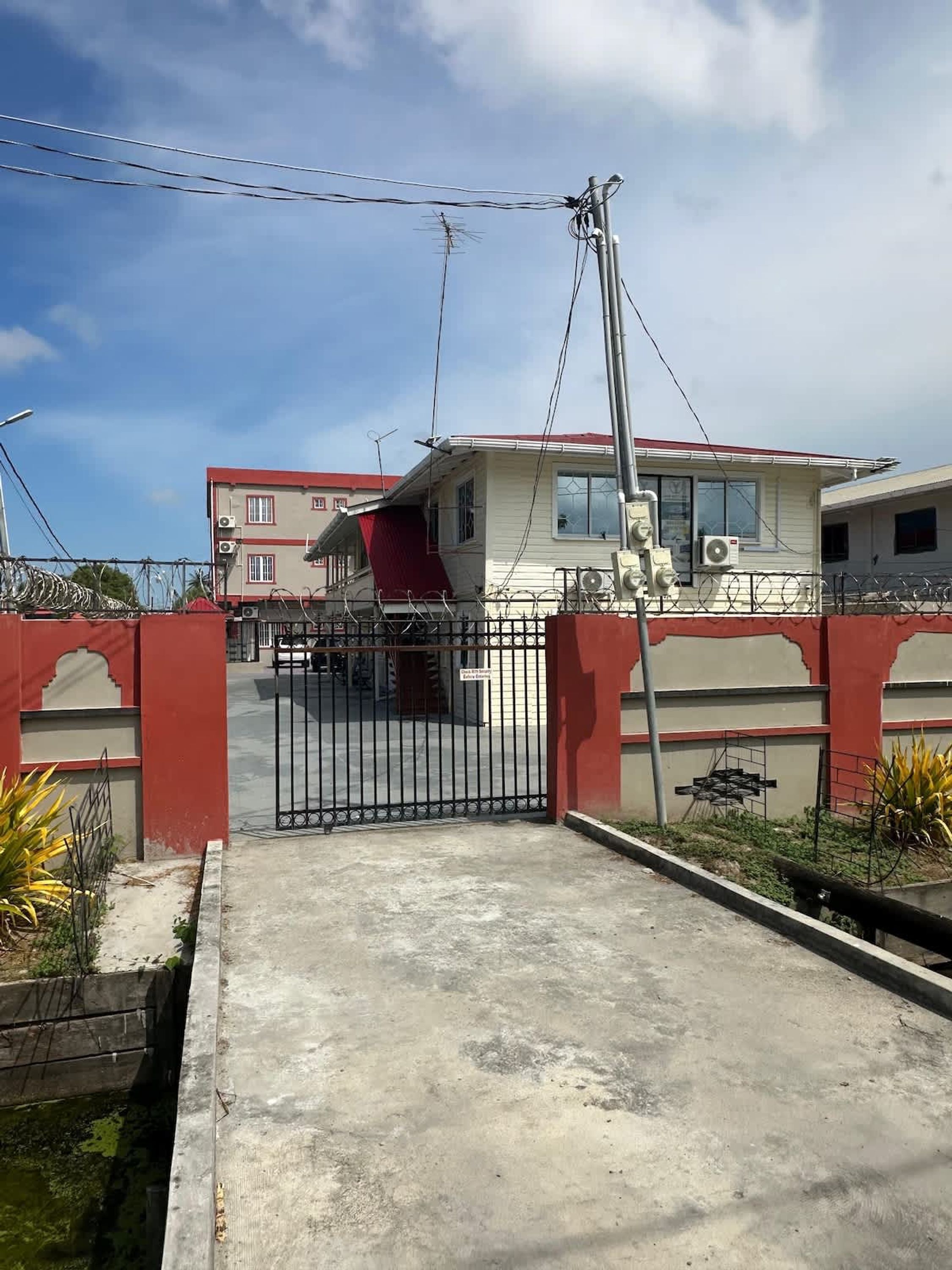 Un conjunto residencial amurallado con un edificio de techo rojo y paredes color crema.