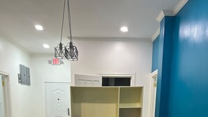 A dining area with a table and chairs, a bookshelf, and a blue wall. - Senior Suite 3 Bedroom (Georgetown)