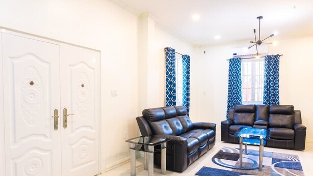 A living room with two leather sofas, a glass coffee table, and a patterned rug. - Senior Suite 3 Bedroom (Georgetown)