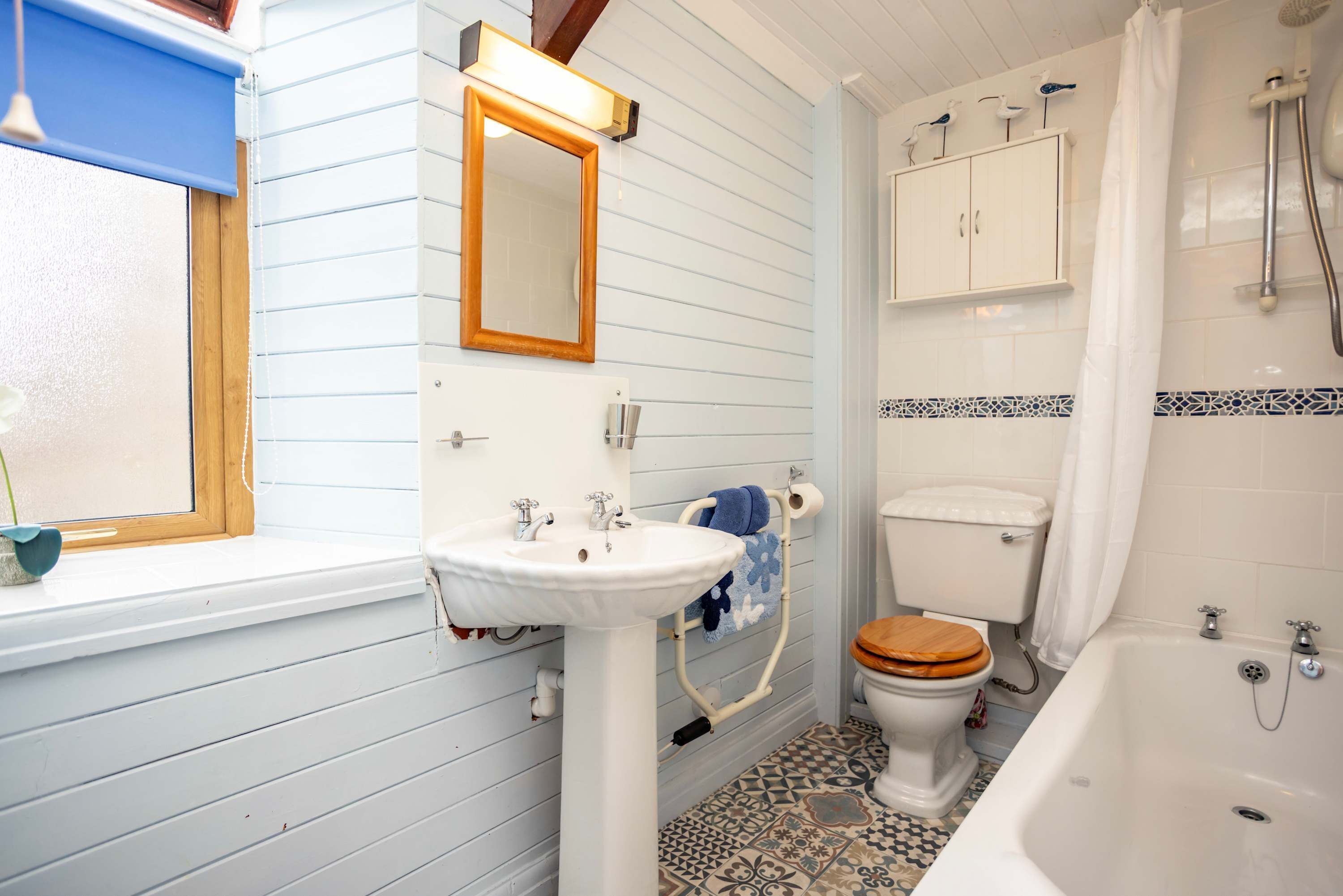 A bathroom with a wooden window, a sink, a toilet, and a bathtub.