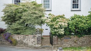 A white building with a stone wall, a gate, and a sign reading "HALL HOUSE". - Hall House 3 Bedroom House St Florence (Tenby)