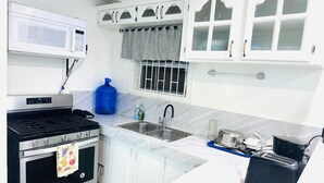 A kitchen with white cabinets, a microwave, a stove, a sink, and a toaster. - Junior Suite in Pigeon Island (Georgetown)