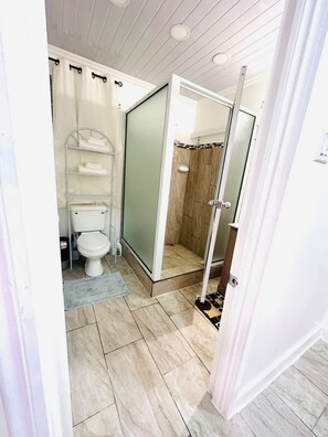 A bathroom with a toilet, shower, and a towel rack. - Junior Suite in Pigeon Island (Georgetown)
