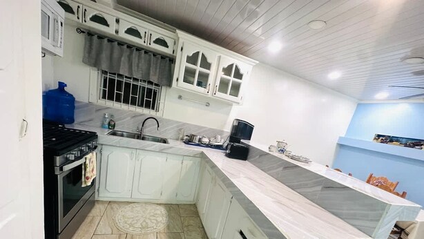 A modern kitchen with white cabinets, a black stove, and a marble countertop. - Junior Suite in Pigeon Island (Georgetown)