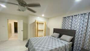 A bedroom with a bed, a ceiling fan, a wardrobe, and a nightstand. - Gentlemen s Suite 3 Bedroom (Georgetown)