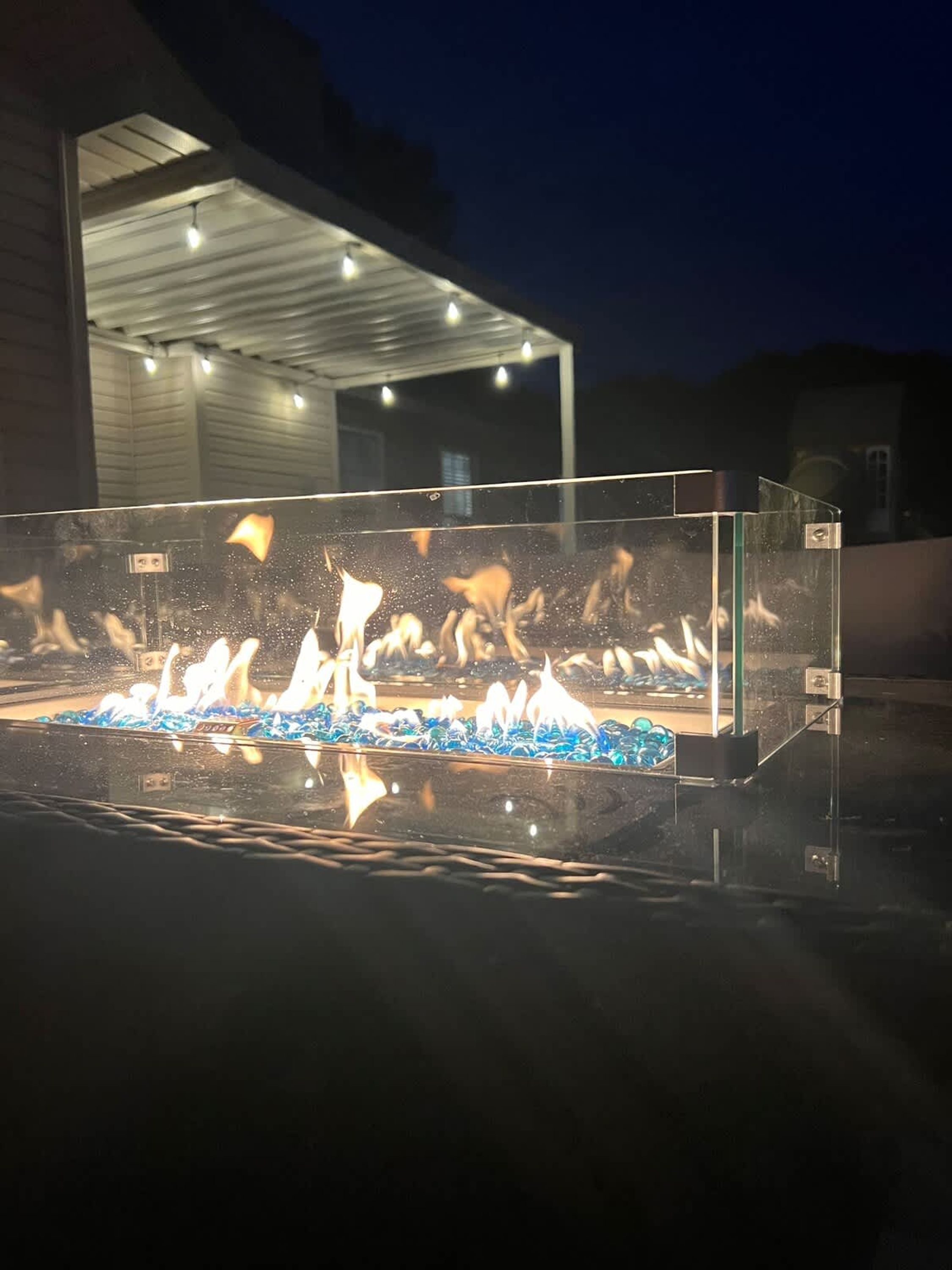 A clear glass enclosure with a water feature and fire elements, likely a decorative outdoor feature.