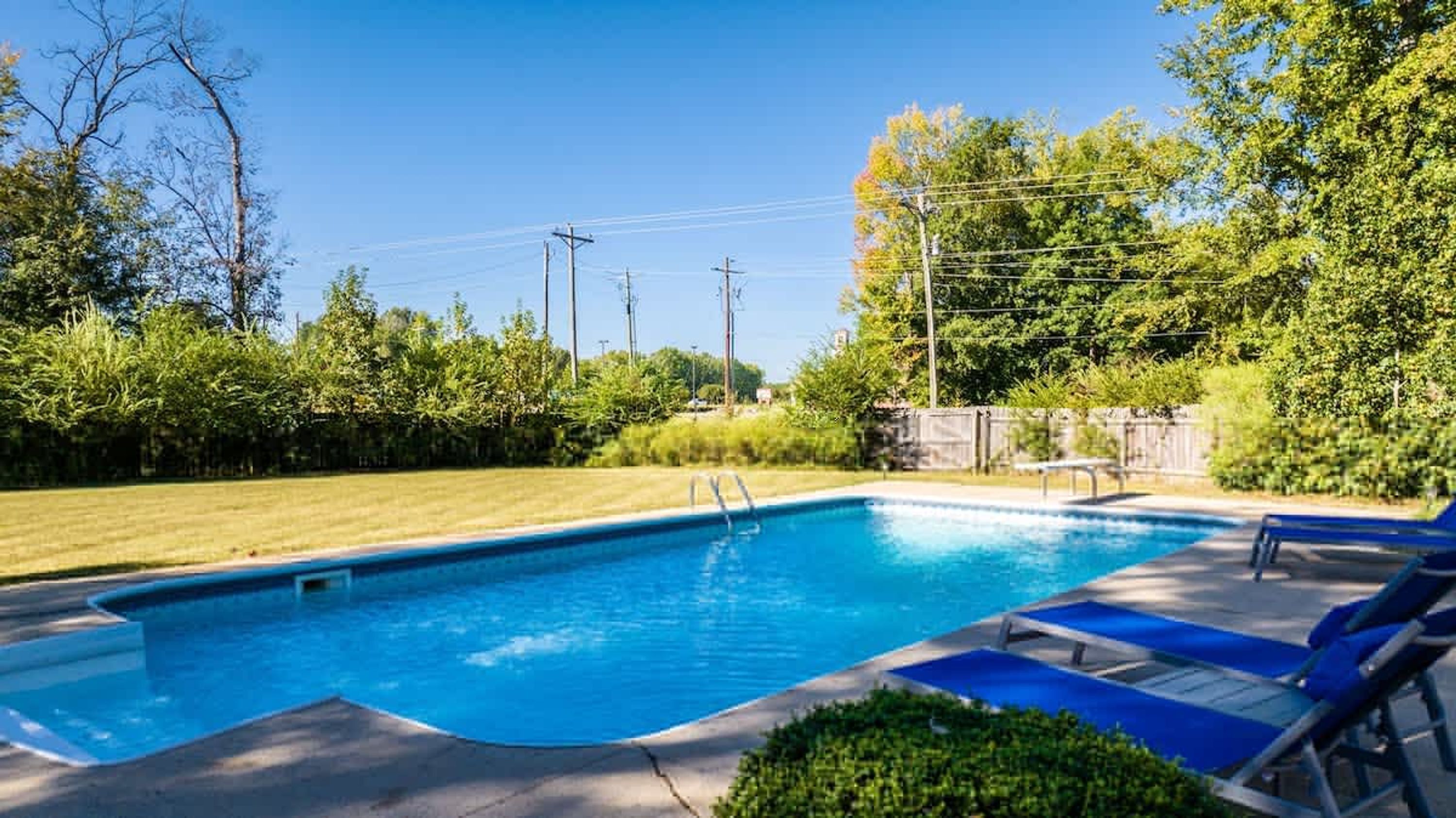 Una piscina rectangular con superficie de agua azul cristalina, rodeada por una solana empavedada.