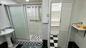 Ένα μπάνιο με καρό δάπεδο, έναν νιπτήρα, μια τουαλέτα και μια περιοχή με ντους.