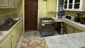 Μια κουζίνα με εστία, νεροχύτη, ντουλάπια και φούρνο μικροκυμάτων.