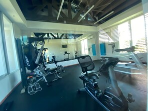 A gym with cardio equipment, weight machines, and a mirror. - Villa De Palma - Oceanfront Community w Generator (Vega Alta)