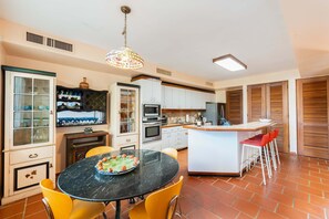 A kitchen with a dining area, featuring a round table, chairs, and a central island with stools. - Villa De Palma - Oceanfront Community w Generator (Vega Alta)