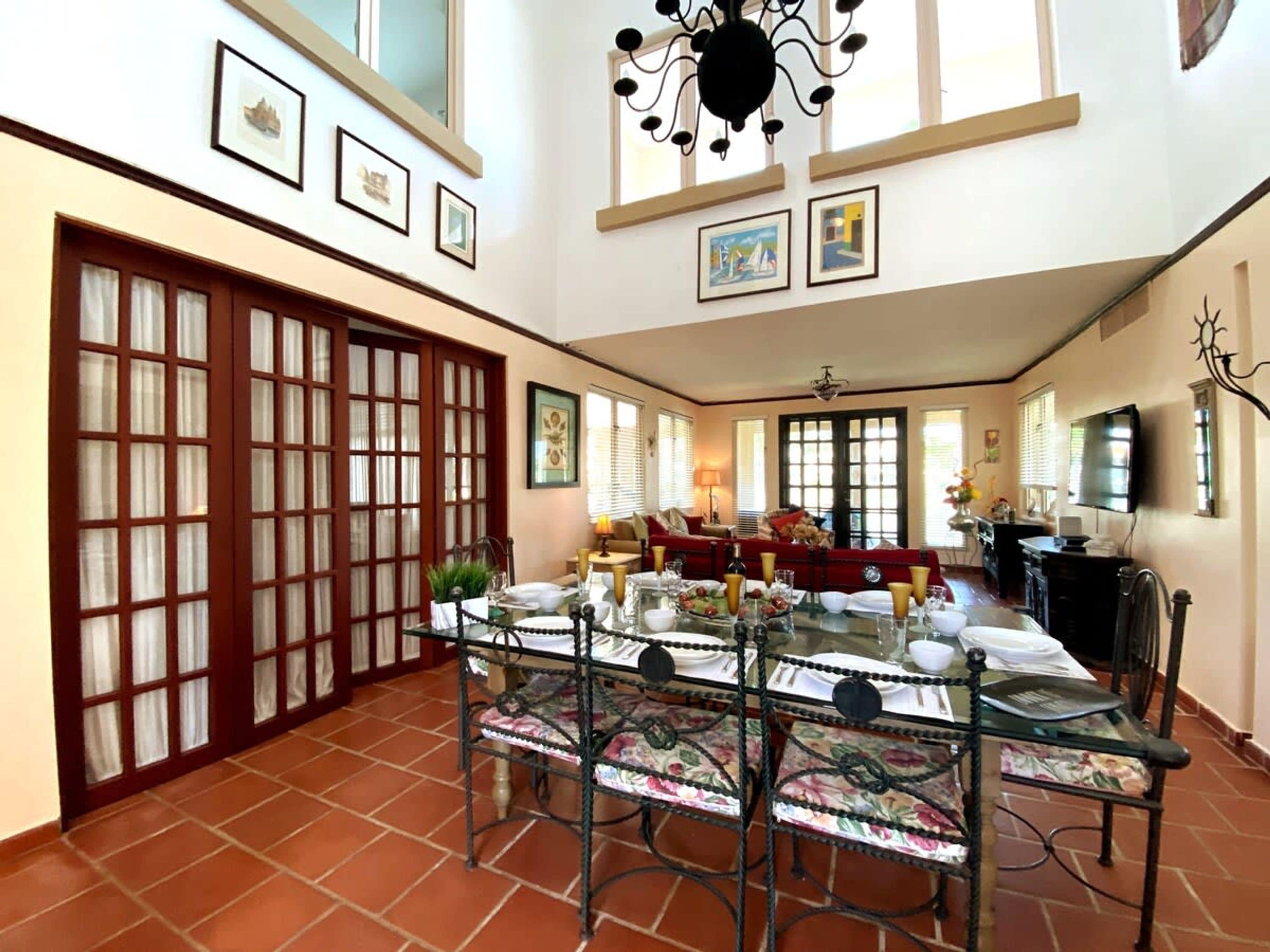 Uma área de refeições com mesa de vidro, cadeiras e sofá vermelho.