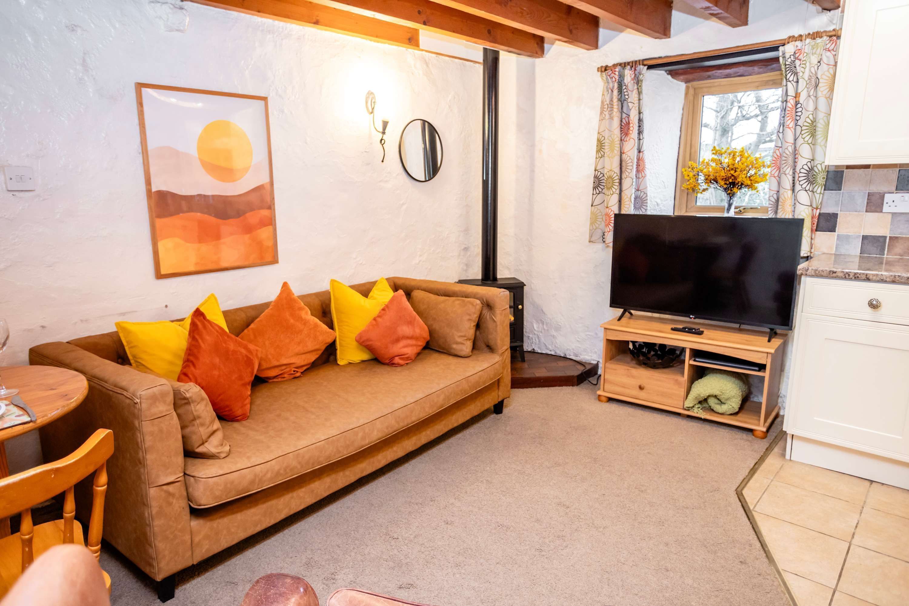 A cozy living room with a sofa, TV, and a window with curtains.