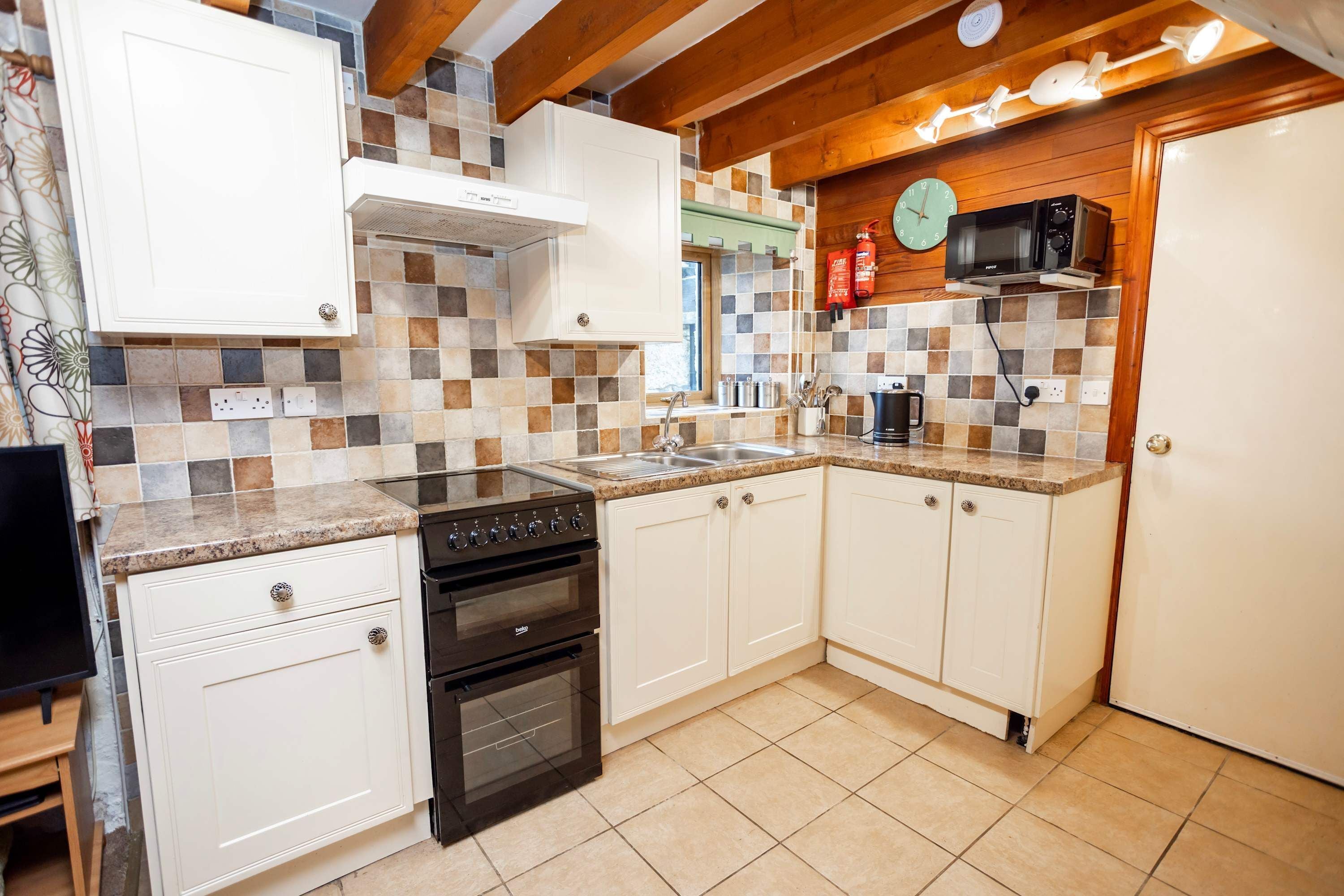 A compact kitchen with white cabinets, a stove, oven, and a microwave.