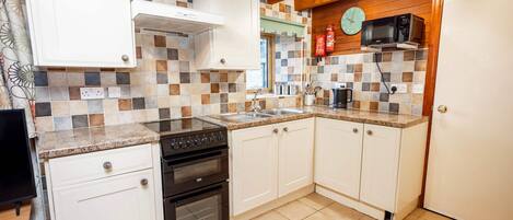 A compact kitchen with white cabinets, a stove, oven, and a microwave.