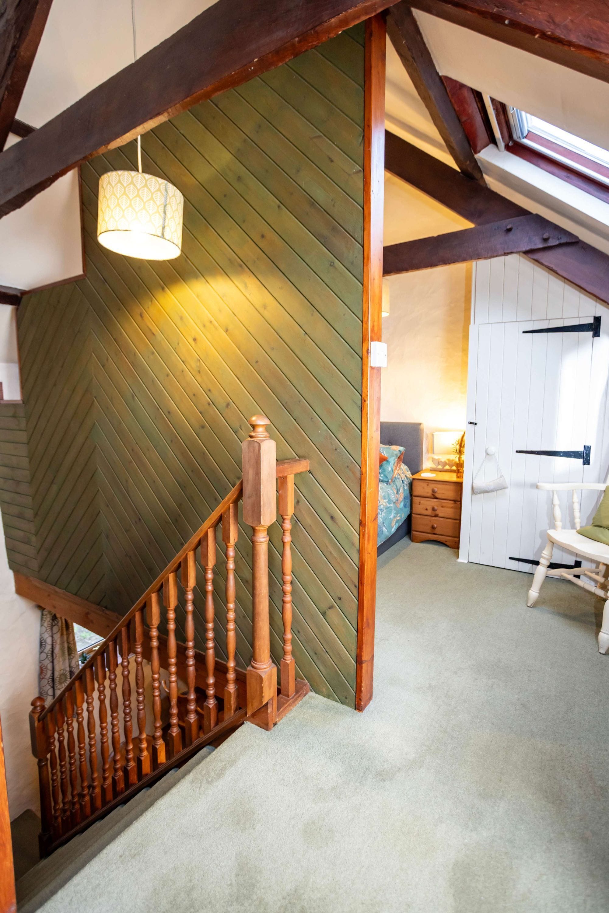 A wooden staircase with a herringbone-patterned wall and a hanging light fixture.