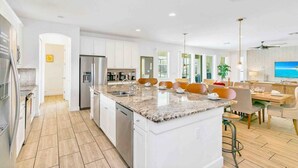 A modern kitchen with white cabinets, a granite countertop, and stainless steel appliances. - Super Size - 11br Spacious Home w Pool HOT TUB (Kissimmee)