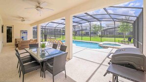 A covered patio with a glass enclosure, a pool, and a barbecue grill. - Super Size - 11br Spacious Home w Pool HOT TUB (Kissimmee)