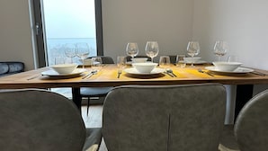 A dining area with a long table set for four, equipped with white bowls, plates, and cutlery.