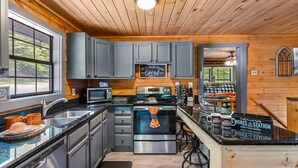 A kitchen with modern appliances, a chalkboard sign, and a cozy seating area with a view.