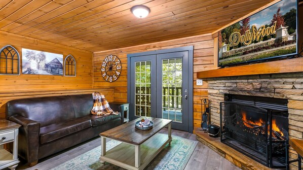L’intérieur chaleureux d’un chalet avec un canapé en cuir, une table basse, une cheminée et une horloge au mur.