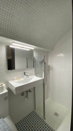 A modern bathroom with a white sink, mirror, and shower.