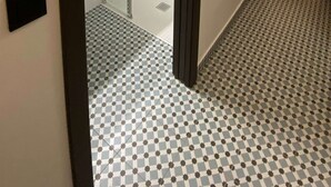 A modern bathroom with a glass shower enclosure, a white sink, and a checkered floor pattern. - Fisherman s Albufeira Cosy Studio (Albufeira)