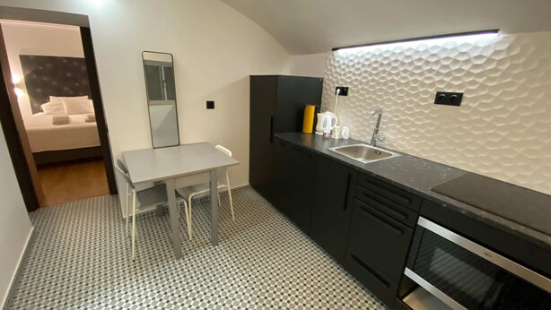 A modern kitchen with a checkered floor, a small dining table, a sink, and a microwave. - Fisherman s Albufeira Cosy Studio (Albufeira)