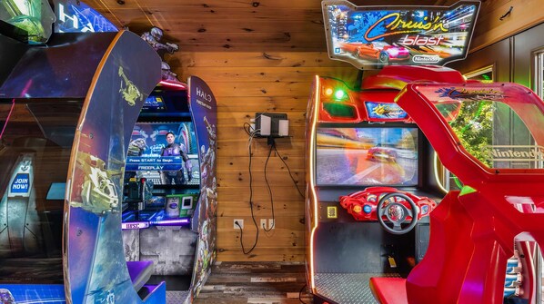 Une salle équipée de plusieurs bornes d’arcade, dont une sur le thème de Halo et une autre proposant un jeu de course.