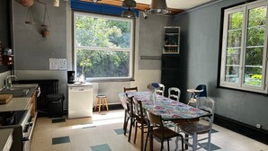 A kitchen with a dining table, chairs, a window, and a refrigerator. - Ancienne Orangerie Du Chateau (Les Hauts-de-Caux)