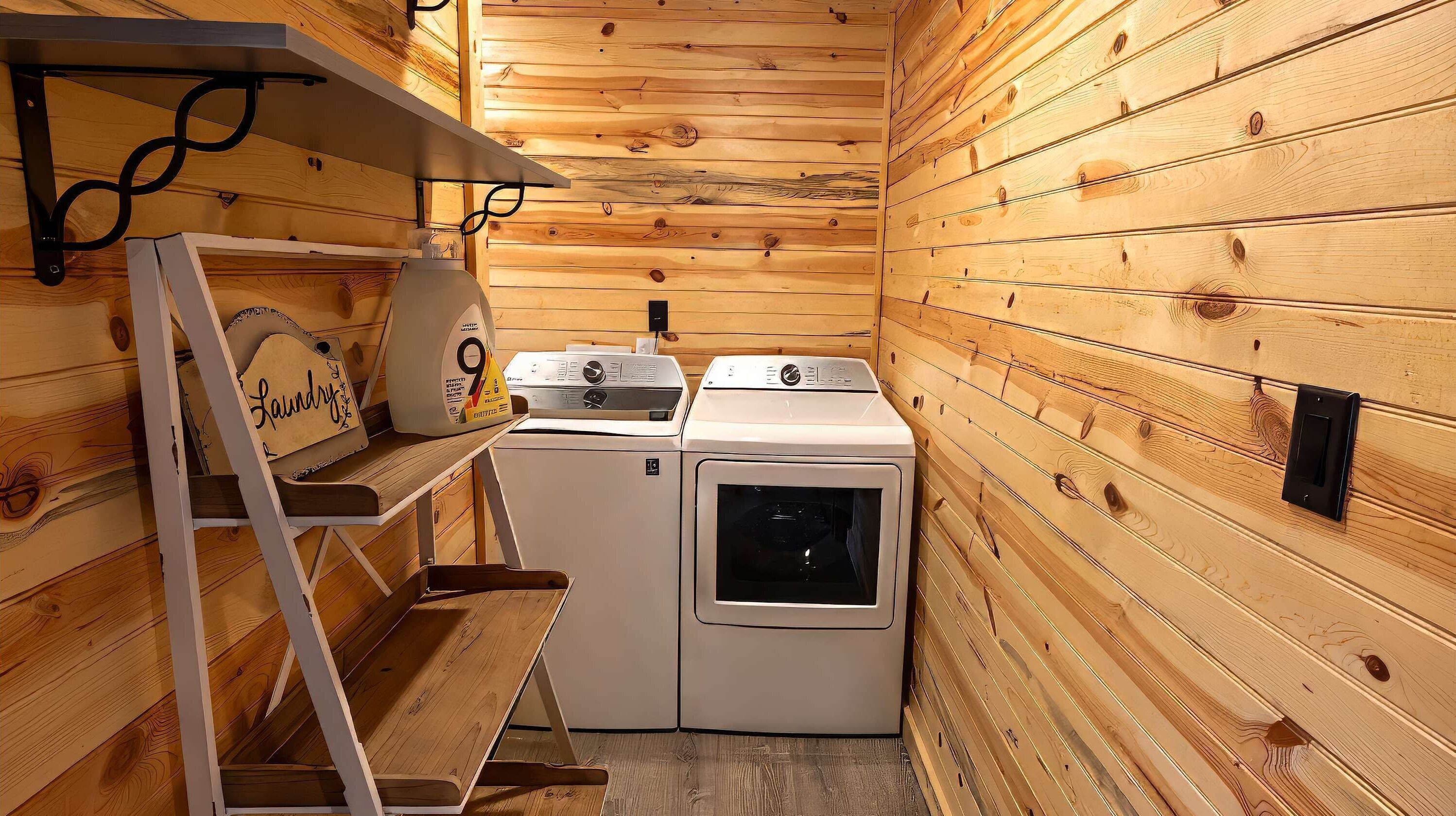 A compact laundry area with a washing machine, dryer, and a shelf with a towel and a sign.