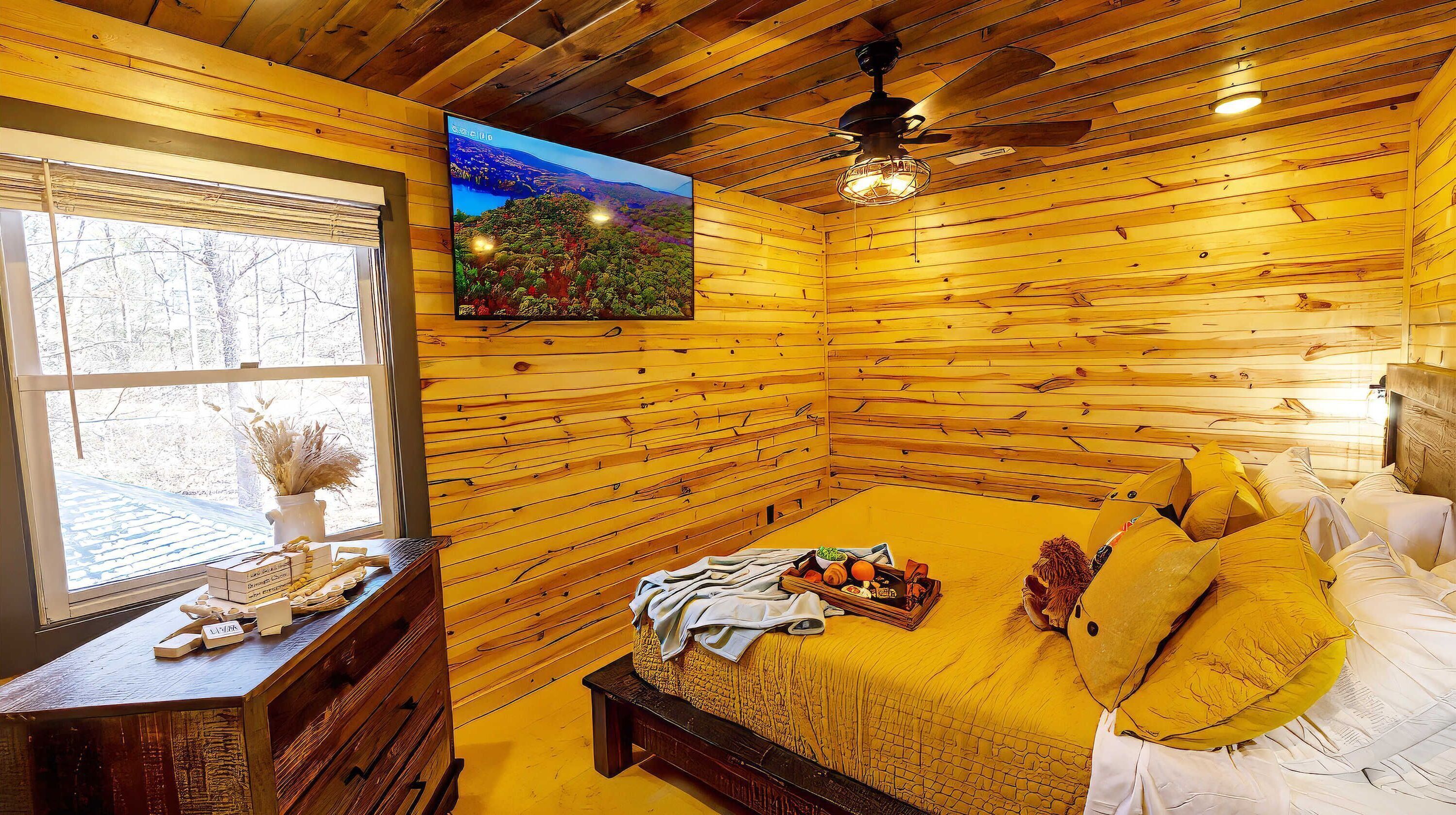 Ein gemütliches Holzhütten-Zimmer mit Bett, kleinem Tisch und Fernseher an der Wand.