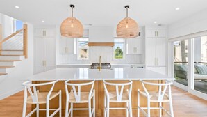 A modern kitchen with white cabinetry, a central island with bar stools, and pendant lighting. - Stareway to Heaven in Fairfield (Fairfield)