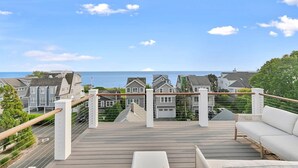 A wooden deck with a white sofa, overlooking a residential area with houses and a view of the sea. - Stareway to Heaven in Fairfield (Fairfield)